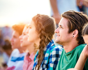Teenagers at summer music festival, sitting on the ground