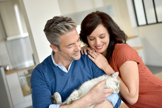 Couple at home cuddling cat