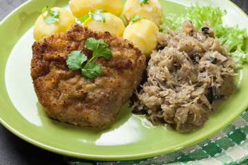 Fried pork schnitzel served with boiled potatoes and fried sauer