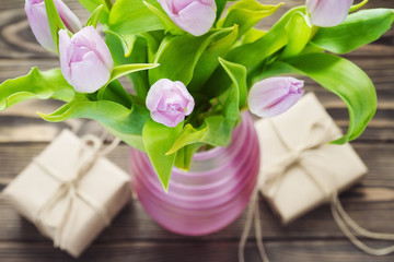 Purple tulips with gifts on the wooden table