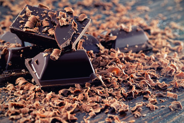 Broken dark chocolate and chocolate shavings on a wooden table