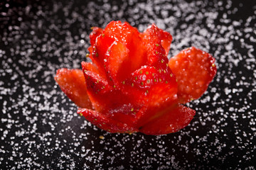 The rose which is cut out from ripe strawberry on a black plate,