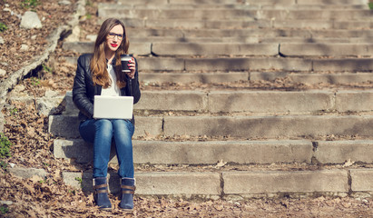Fototapeta premium Young pretty woman having coffee break on stairs