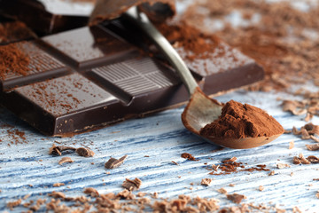 Broken dark chocolate and chocolate shavings on a wooden table