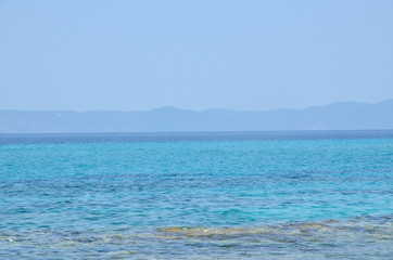 Fototapeta premium Turquoise sea water with land in distance and blue sky