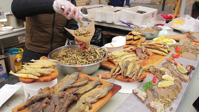 Street food seller putting crispy salty anchovies in package. Appetizing snacks