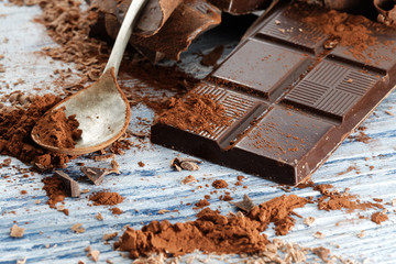 Broken dark chocolate and chocolate shavings on a wooden table
