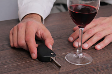 Don't drink and drive concept. Close up of man hand drinking wine and holding car keys. Responsibly and safety driving