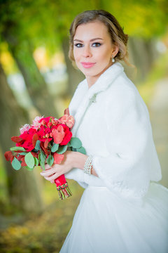 прекрасная невеста в день свадьбы с красным букетом