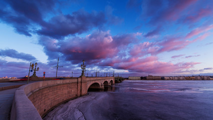 Russia, Saint-Petersburg, 19 March 2016: Pink clouds over the Troitsky Bridge at sunset, drifting ice, frozen Neva River, the traffic on the bridge, a pedestrian walk, Troitskiy © Vladimir Drozdin