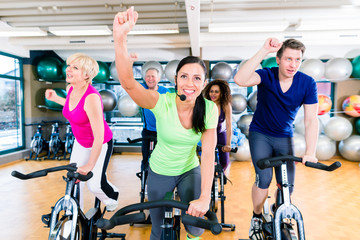 Group of men and women spinning on fitness bikes in gym, diversity people, old, young, black and...