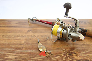fishing lures, rod and reel on wooden background
