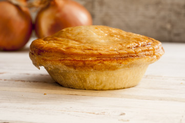 Cooked Pie and Onions on a Smooth Wooden Surface
