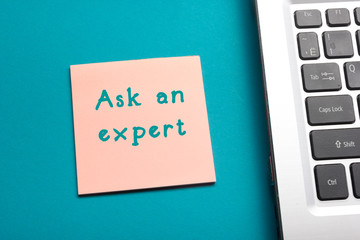 Ask an expert. Office table top view - Laptop and reminder.