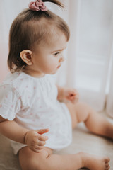 Fototapeta premium Cute little baby girl on the table in the kitchen eats citrus fruits full of vitamins and makes funny cute faces