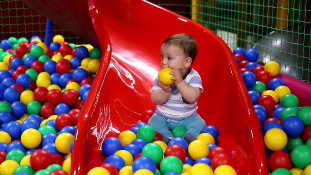 Baby on the chute with balls in playground
