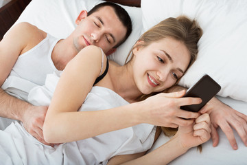 Obraz na płótnie Canvas Wife texting with lover on smartphone