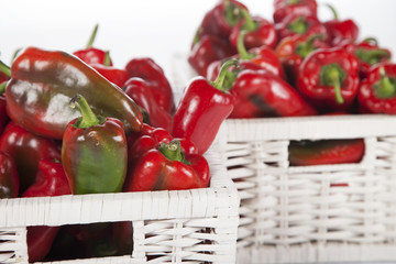 Red bell peppers in a wooden wicker basket isolated on white