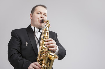 Fototapeta premium Music Concept and Ideas. Portrait of Caucasian Player in Suit Playing Sax