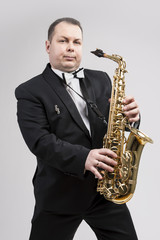 Fototapeta na wymiar Relaxing Caucasian Man Posing With Saxophone Against White Background