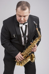 Naklejka premium Caucasian Man in Suite with Saxophone. Posing Against White.