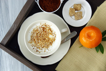 A morning breakfast tray with milk, granola, coffee, orange and sugar.