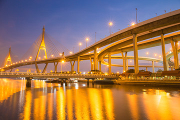 Modern Suspension bridge and highway curved riverside at twilight scene with golden light