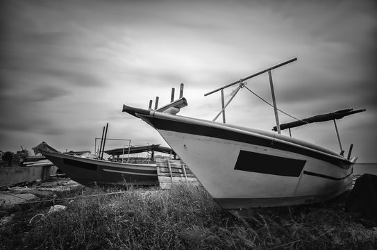 black and white fisherman boat on the shore with soft clouds background due to long exposure shot.