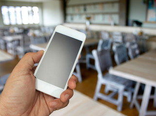 hand holding the smartphone on blur restaurant background