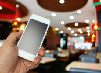 hand holding the smartphone on blur restaurant background