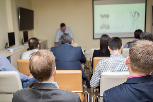 Person delivering a speech. Audience at a conference presentation.