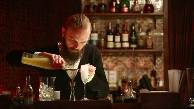 Handsome barman professional at posh bar making cocktail drinks