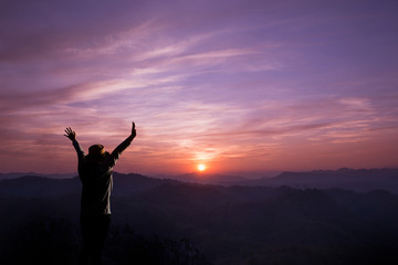 Young woman cheering open arms at mountain and sunset