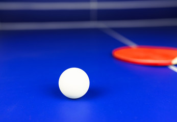 White Table Tennis Ball and a Red Racket on a Blue Table