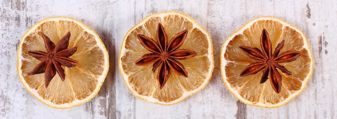 Slices of dried lemon and star anise on old wooden background