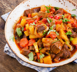 Beef stew with vegetables on a wooden table.