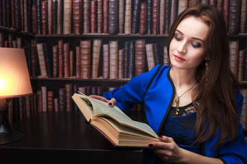 Beautiful girl with a book on the background of bookshelves, with free space for your text