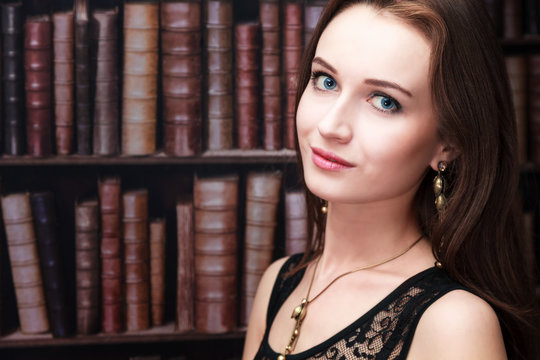 Beautiful girl on the background of bookshelves, with free space for your text