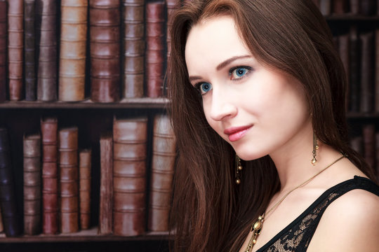 Beautiful girl on the background of bookshelves, with free space for your text