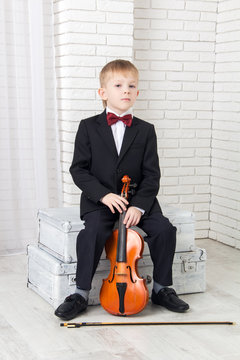 little boy in a suit sitting with violin