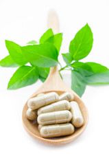 Herbal medicine capsules in wooden spoon.