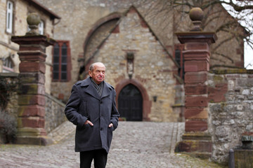 Fototapeta na wymiar Elderly man standing in front of a church in a historic German town