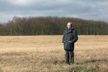 Elderly man standing lonely in a winter landscape