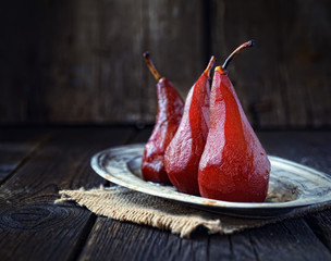 pears in red wine on a vintage plate and wood background