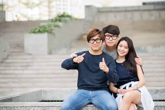 Three Korean teenage friends hugging and looking at camera