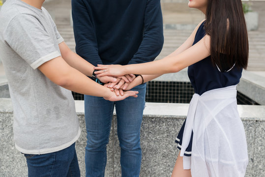 Cropped image of young people staking hands