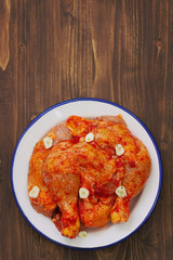 raw chicken with garlic in dish on brown wooden background