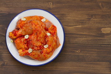 raw chicken with garlic in dish on brown background