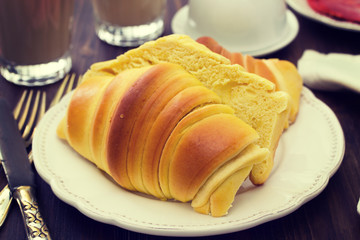 croissant with ham on white plate and glasses of coffee with milk