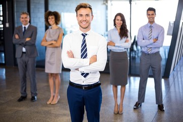 Businessman smiling at camera while his colleagues standing